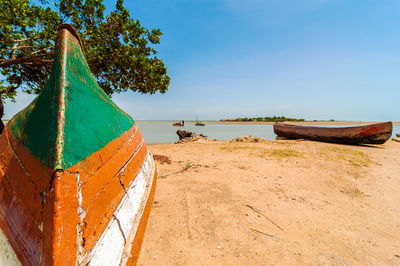 Boats moored at beach against sky on sunny day