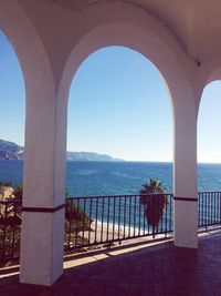 Sea seen through railing against clear sky