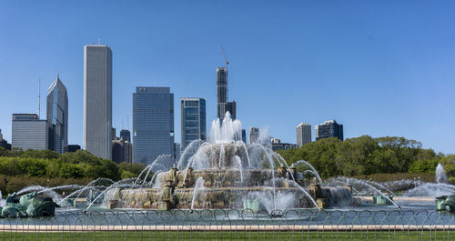 Fountain against clear blue sky in city