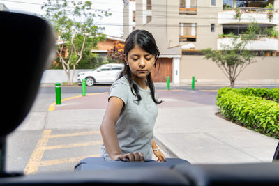 Portrait of young woman standing against trees