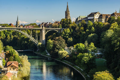 Bridge over river by buildings against sky