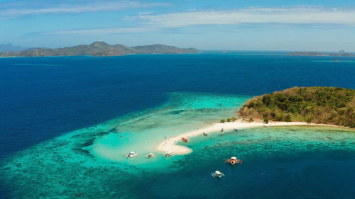 Tropical beach on island ditaytayan. tropical island with white sand bar, palm trees and green hills