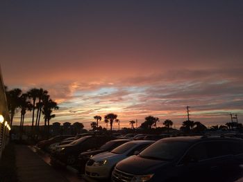 Cars on road against sky during sunset