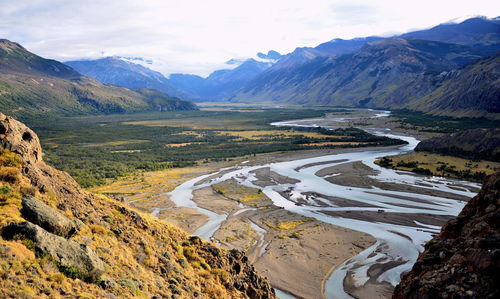 Scenic view of river by mountains against sky