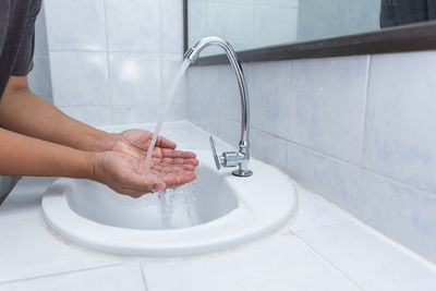 Midsection of man washing hands in bathroom