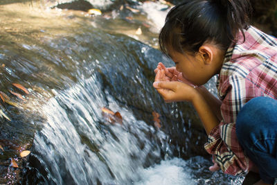 Girl drinking water from waterfall