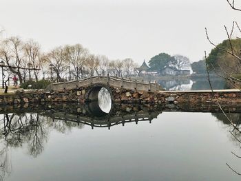 Arch bridge over lake against clear sky