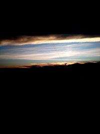 Silhouette landscape against dramatic sky during sunset