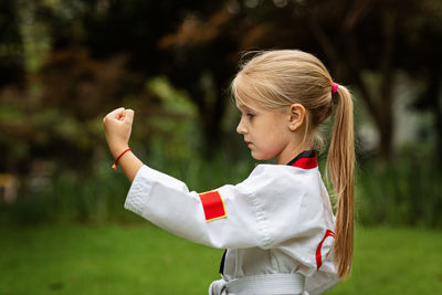 Portrait of young woman with arms raised standing outdoors