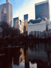 Reflection of buildings in lake against sky in city