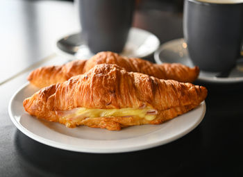 Croissant ham cheese is a france food, croissant with ham and cheese on white plate ,and coffee.