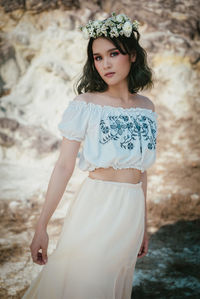 Portrait of beautiful young woman standing against wall