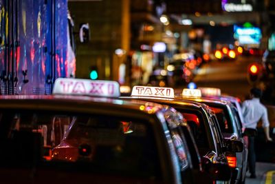 Cars on illuminated city street at night