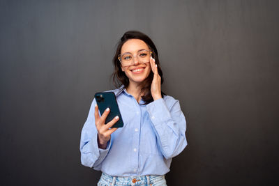 Portrait of young woman standing against black background