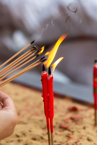 Close-up of hand holding burning candles