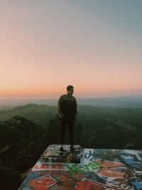 Rear view of man standing on mountain against sky
