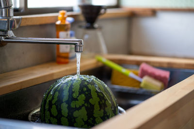 Close-up of fruit under faucet in sink