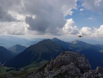 Helicopter flying over mountains against sky