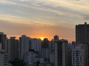 Buildings in city against sky during sunset
