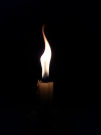 Close-up of lit candle in darkroom