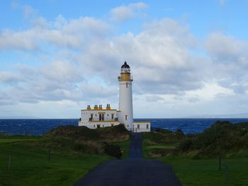 Lighthouse amidst sea and buildings against sky