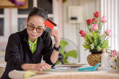 Mid adult woman with credit card sitting at table in office