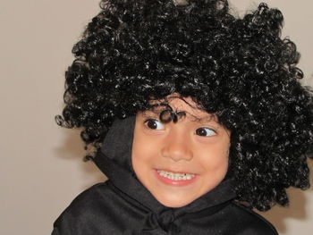 Close-up of cheerful boy wearing wig at home