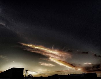 Low angle view of illuminated building against cloudy sky