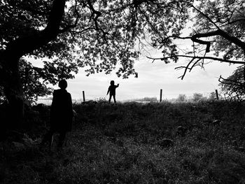 Silhouette people standing on field against sky