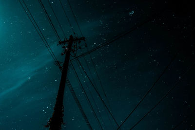 Low angle view of electricity pylon against sky at night