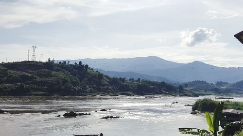 Scenic view of river by mountains against sky