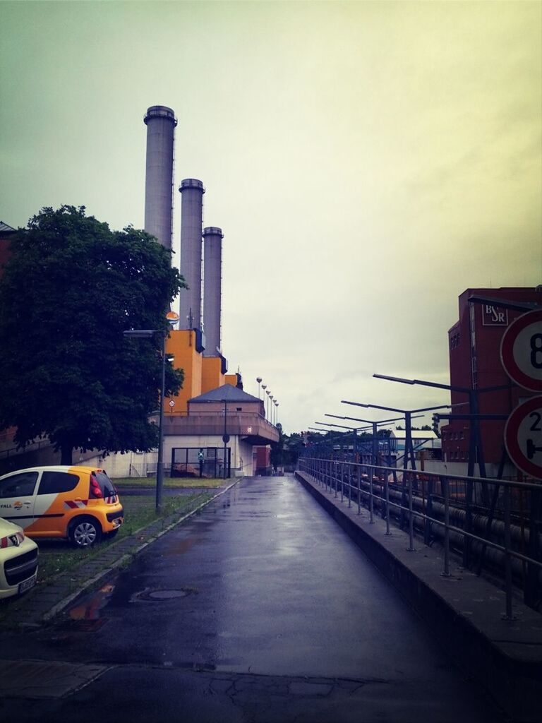 architecture, building exterior, built structure, transportation, city, sky, street, mode of transport, the way forward, land vehicle, car, tree, road, incidental people, diminishing perspective, building, outdoors, city life, city street, road marking