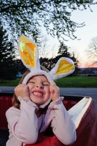 Smiling girl with bunny ears against trees