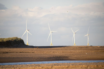 Wind turbines on land against sky