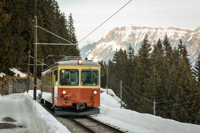 Train on railroad track by mountain during winter