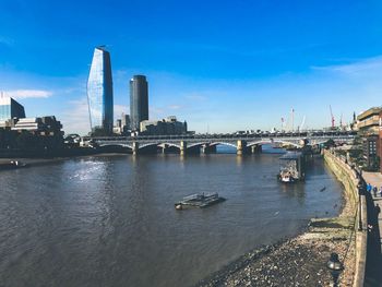 Bridge over river in city against sky