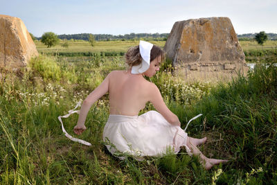 Shirtless woman sitting on land