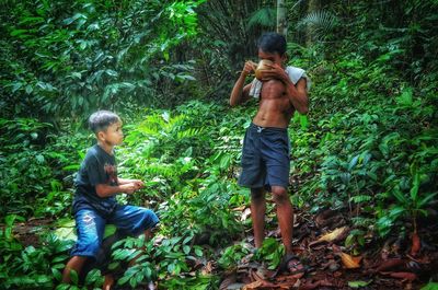 Full length of shirtless boy in forest