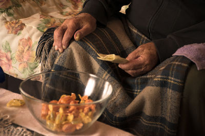Midsection of senior man with food in bowl on table