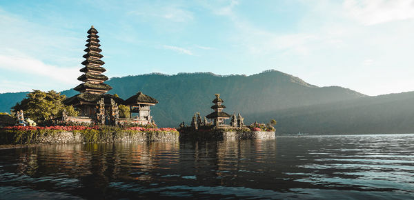 Traditional building by lake against sky