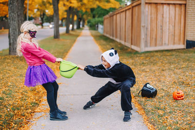 Full length side sibling wearing bucket playing on footpath