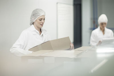 Woman in protective workwear lifting cardboard box