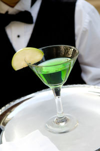 Midsection of waiter holding martini glass