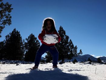 Full length of girl playing with snow against clear blue sky