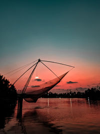 Silhouette pier over lake against sky during sunset