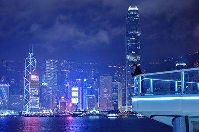 Illuminated modern buildings in city against sky at night