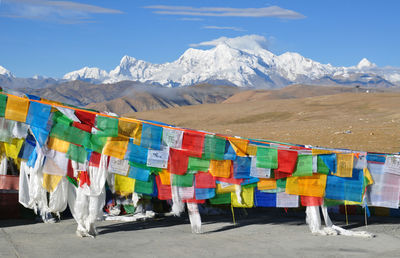 Multi colored flags hanging against mountain