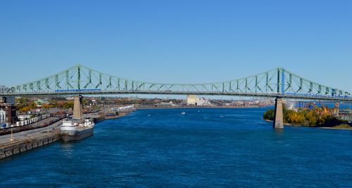 Suspension bridge over river against clear blue sky