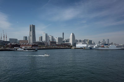 View of city at waterfront against cloudy sky