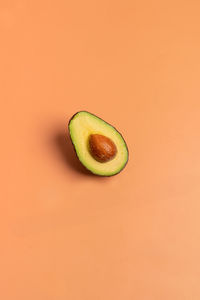 Close-up of minimalist avocado against orange background 